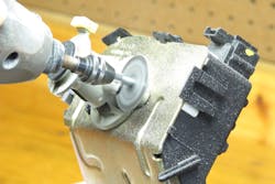 Image 7: A Dremel tool that has a cut-off wheel is used to remove the top portion of the chamber that contains the spring-loaded retainer. After the top has been removed, the spring can be removed. Image 7: A Dremel tool that has a cut-off wheel is used to remove the top portion of the chamber that contains the spring-loaded retainer. After the top has been removed, the spring can be removed.